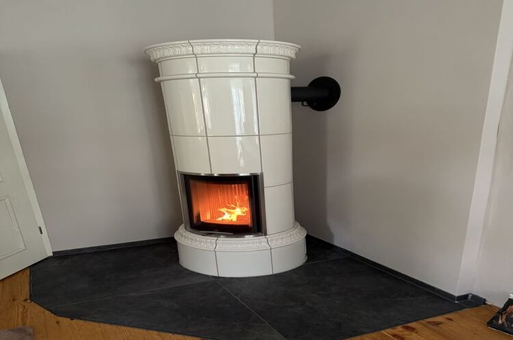 Weißer Kachelofen mit Feuer im modernen Wohnzimmer sorgt für gemütliche Wärme und Ambiente.